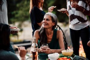 woman at a table outside enjoying a drink and veggies and dips