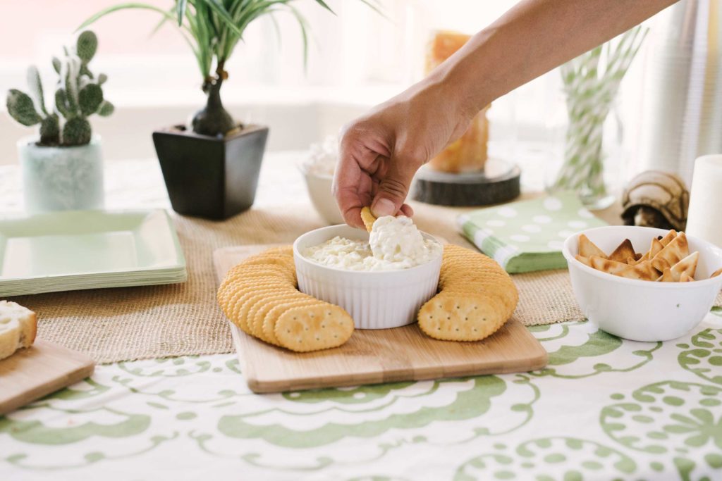 hand dipping a cracker in La Terra Fina Dip