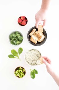hands dipping bread in a bowl of La Terra Fina Dip