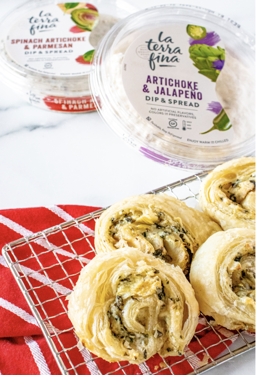 Spinach & Artichoke Pinwheels on a cooling rack with the dip