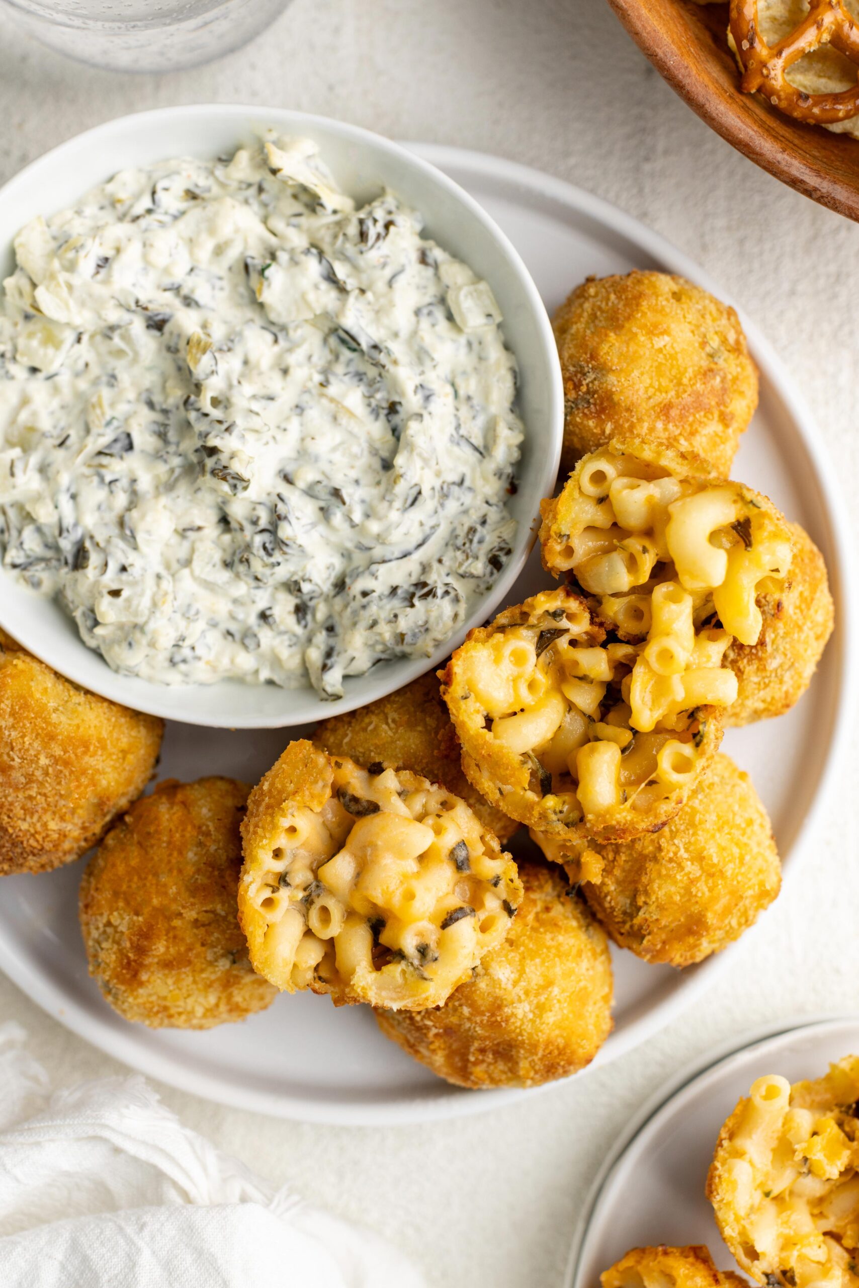 spinach artichoke mac cheese balls next to a bowl of dip