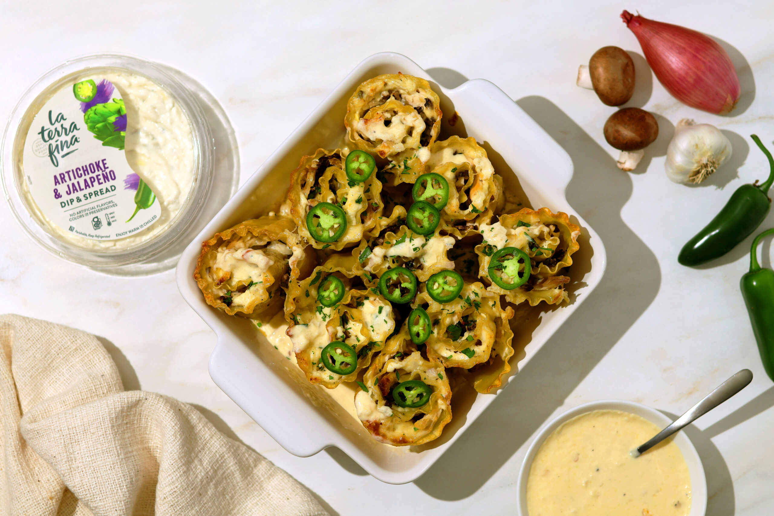 Artichoke Jalapeño Roll-up Casserole on a counter with Artichoke & Jalapeno Dip